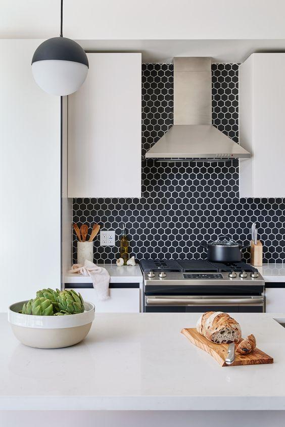 Cozinha em estilo moderno com revestimento hexagonal azul na parede da pia, armários e bancadas brancas com eletrodomésticos de inox.