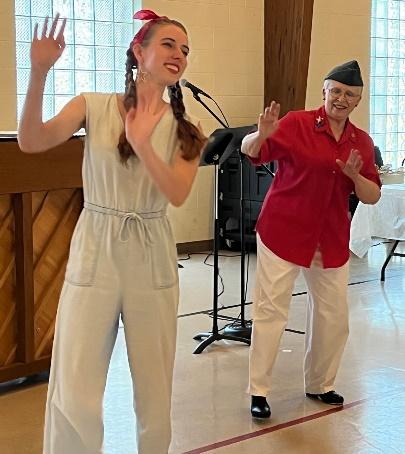 A person in white jumpsuit and red headband dancing with an older person 
Description automatically generated