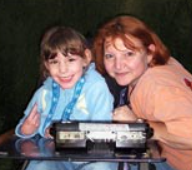 picture of young camper, her AAC system and Kelly at Building Bridges Camp in early 2000s