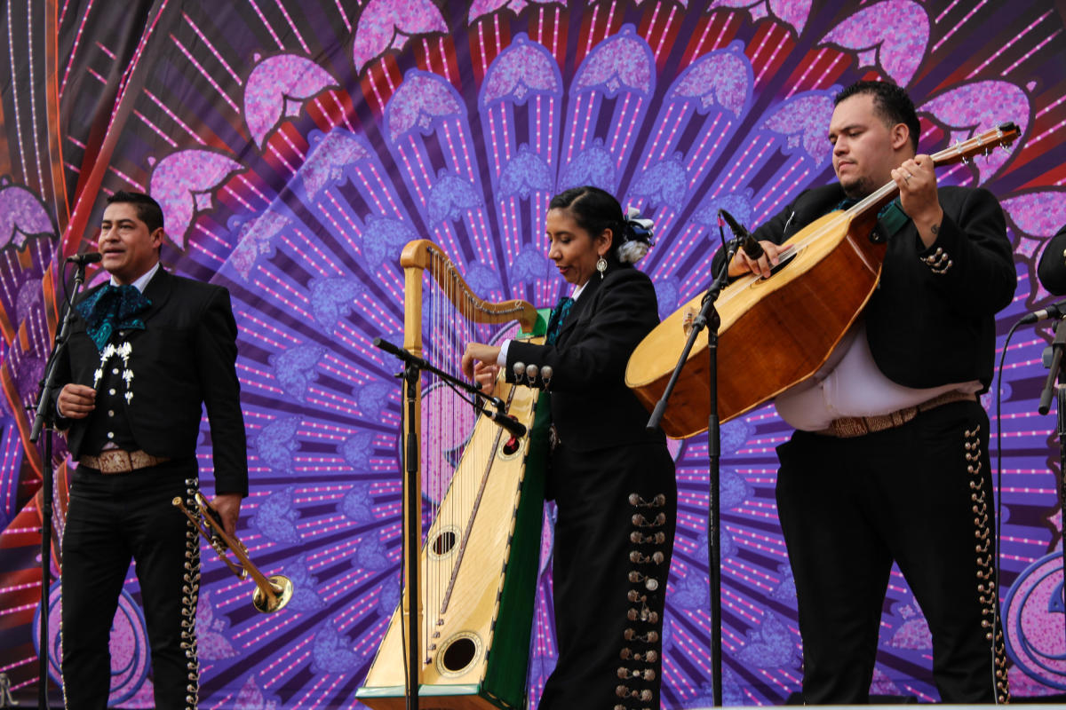 Hispanic band playing instruments on a stage with a purple background