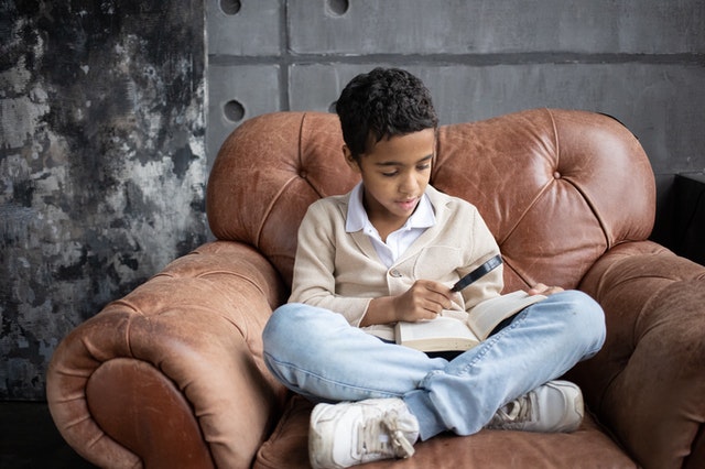 Boy-Reading-On-A-Couch-Stock