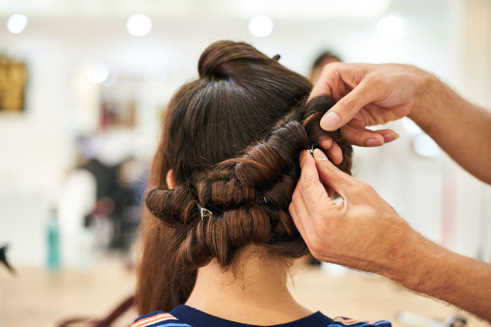 Hair stylist pins curls of a brunette client