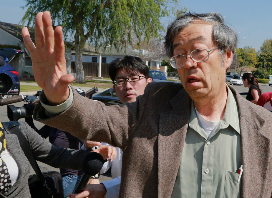 Дориан Сатоши Накамото пытается выйти из своего дома, окруженного журналистами