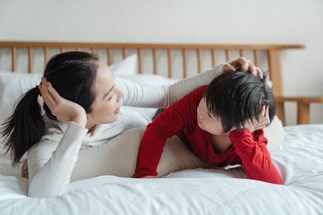role of parents in their child's education, this image shows a woman and her child talking on the bed