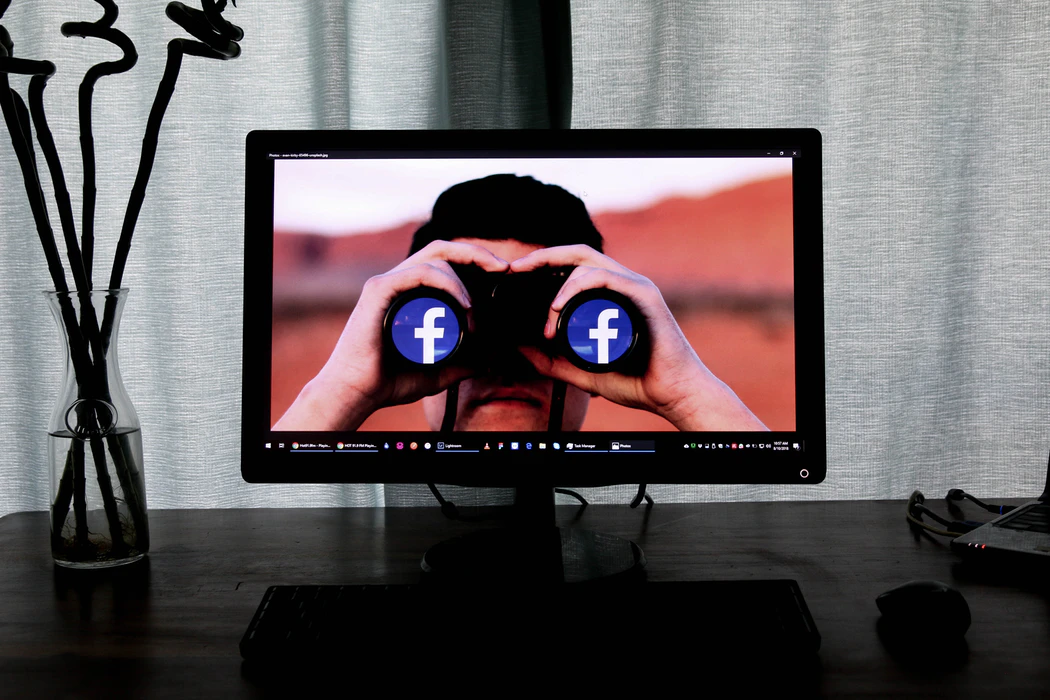 Desktop monitor with a wallpaper of a man looking through binoculars, a depiction of social stalking