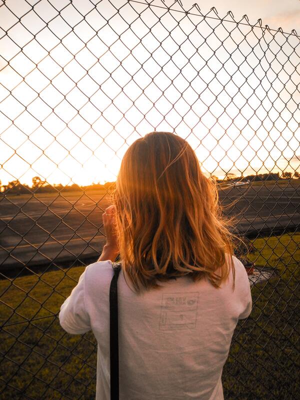 Foto de uma menina de costas olhando para o por-do-sol 