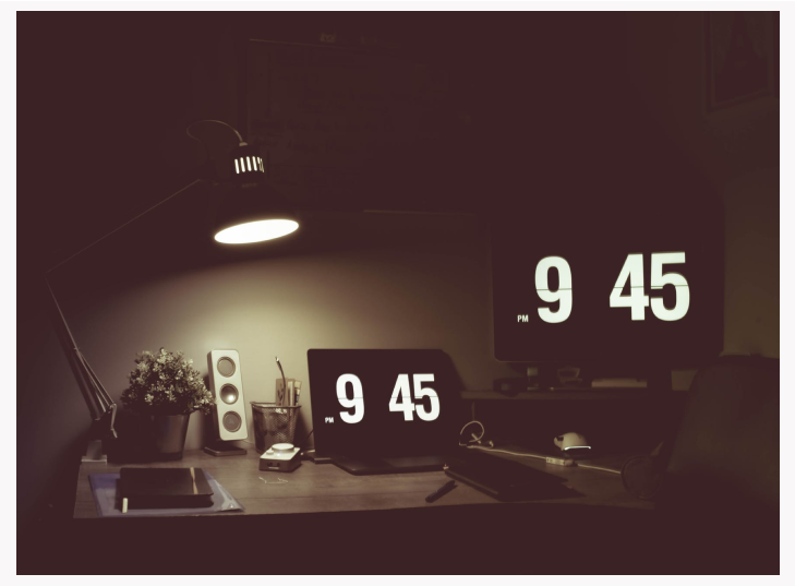 A dark desk faintly illuminated by a desk lamp.