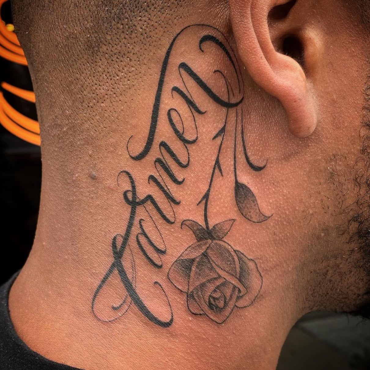 Script Rose Behind The Ear Tattoo