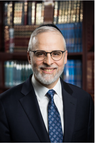 A person wearing glasses and a suit  Description automatically generated with medium confidence
