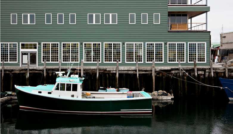 A lobster boat docked by a shipyard building in Old Port