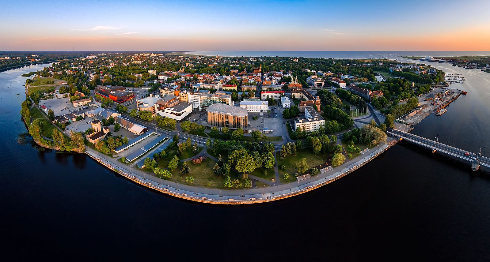 aerial view of parnu. waterfront buildings and parks, bridge connecting to mainland. sunset in estonia.