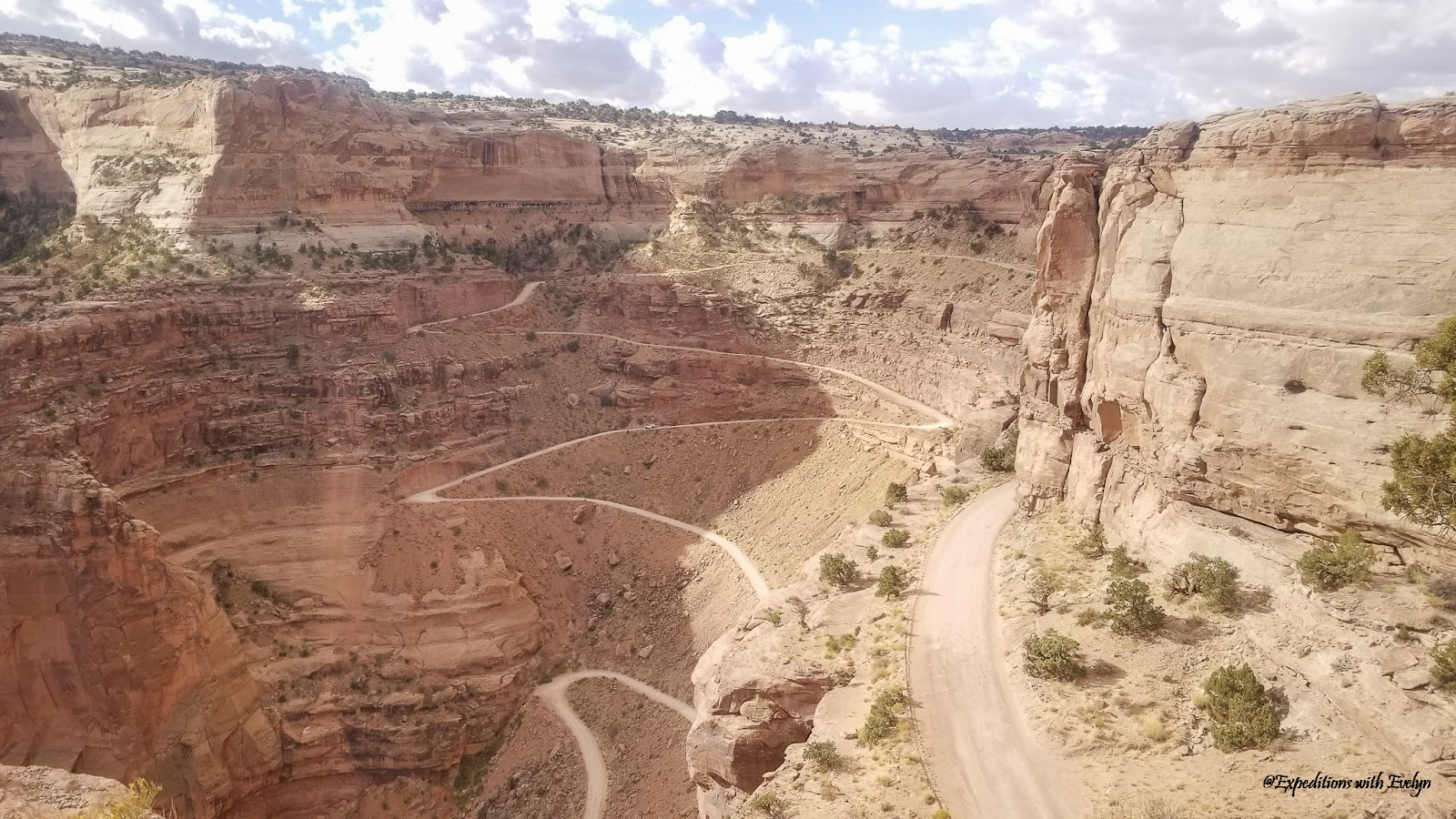 A winding dirt road full of switchbacks descends down into a canyon.  Driving this is on of the most unique things to do in Moab Utah.