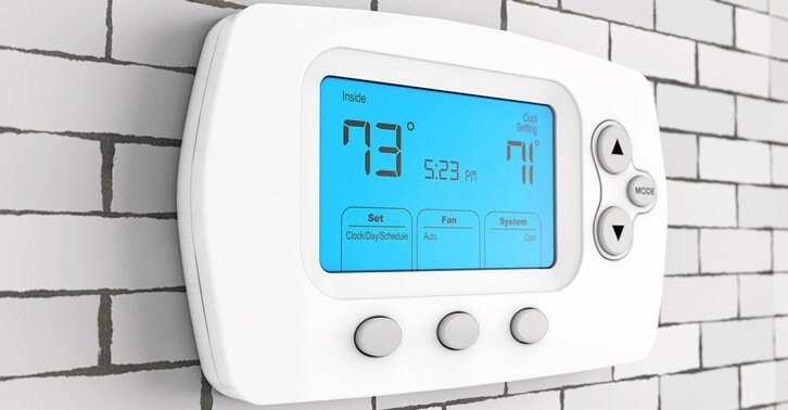 Photo of. a modern domestic thermostat control mounted on a wall.