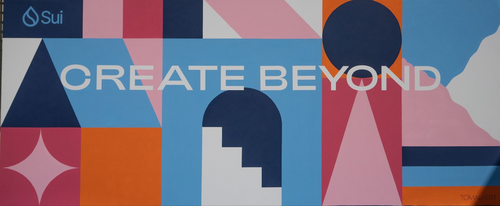 一张几何壁画，上面写着 "创造超越"（Create Beyond）。