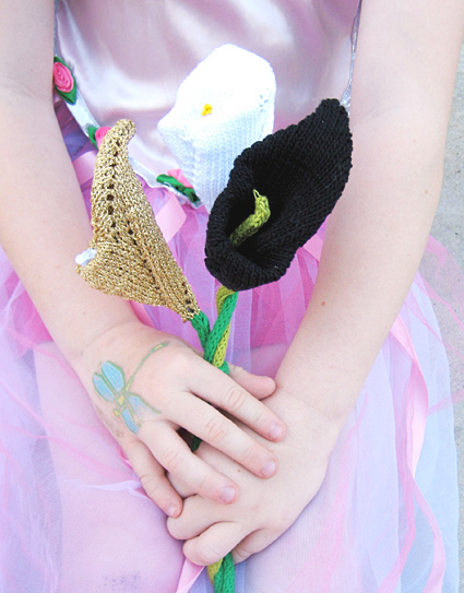 three colors of knitted calla lilies held in a bouquet