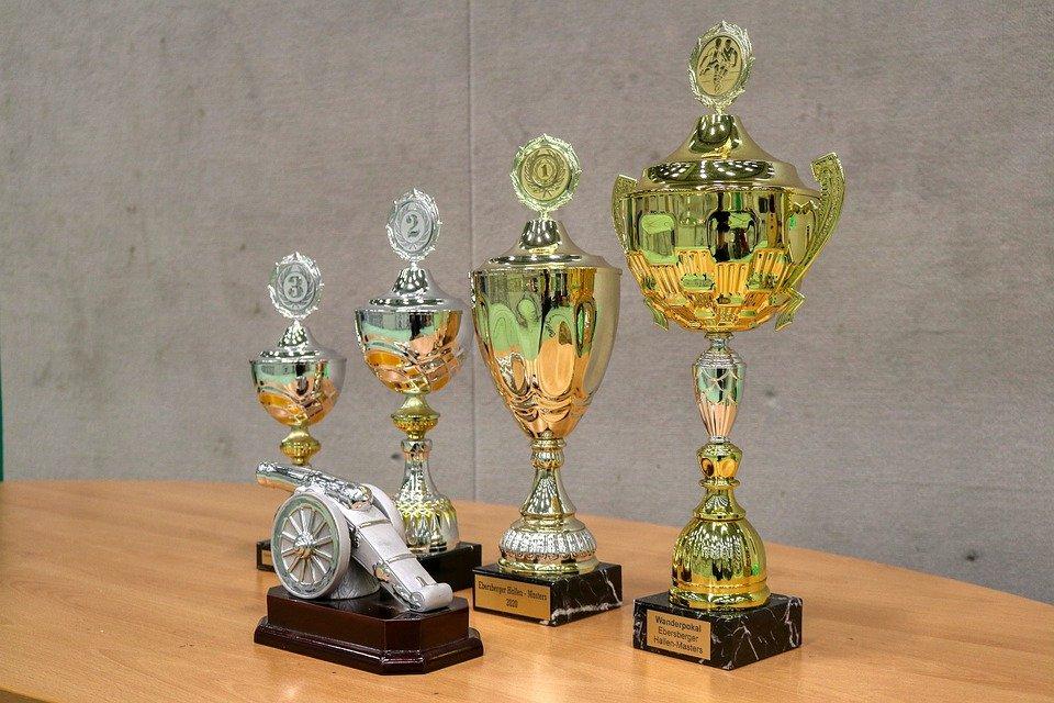 Four trophies with different sizes placed on the top of a table