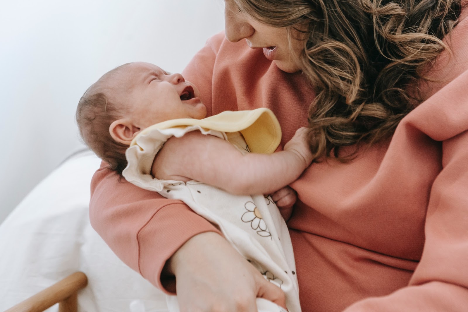 Infant teacher holding crying infant 