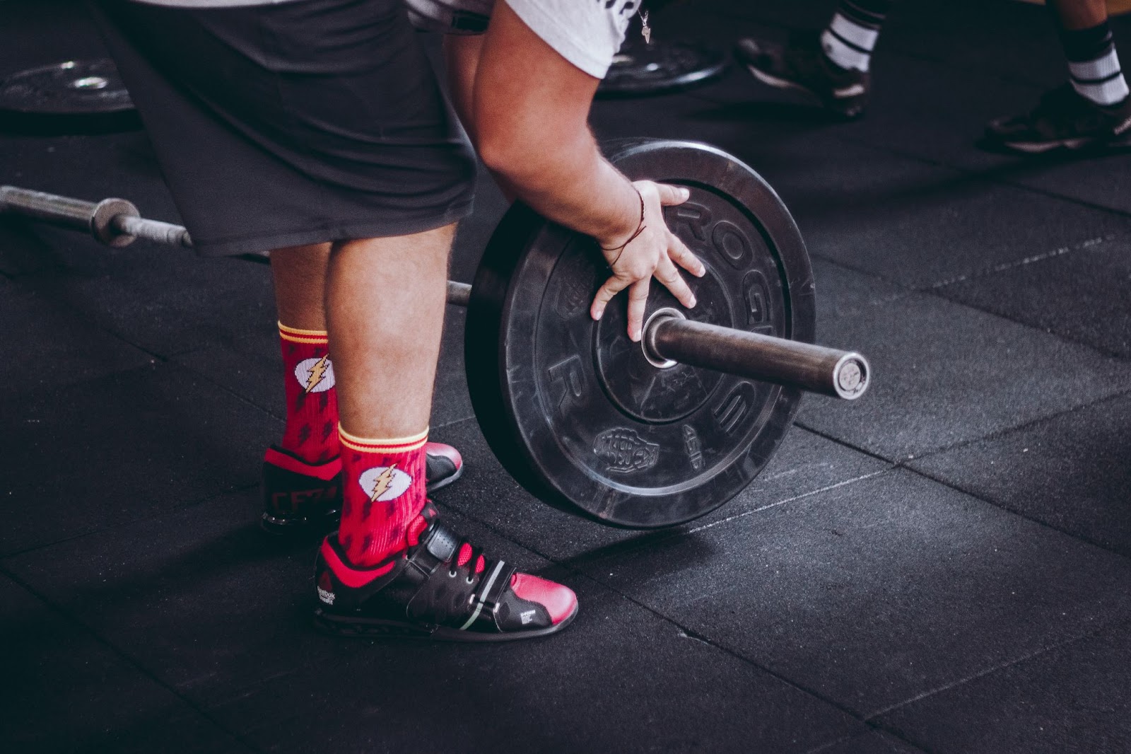weightlifter in red socks putting a weight plate on barbell