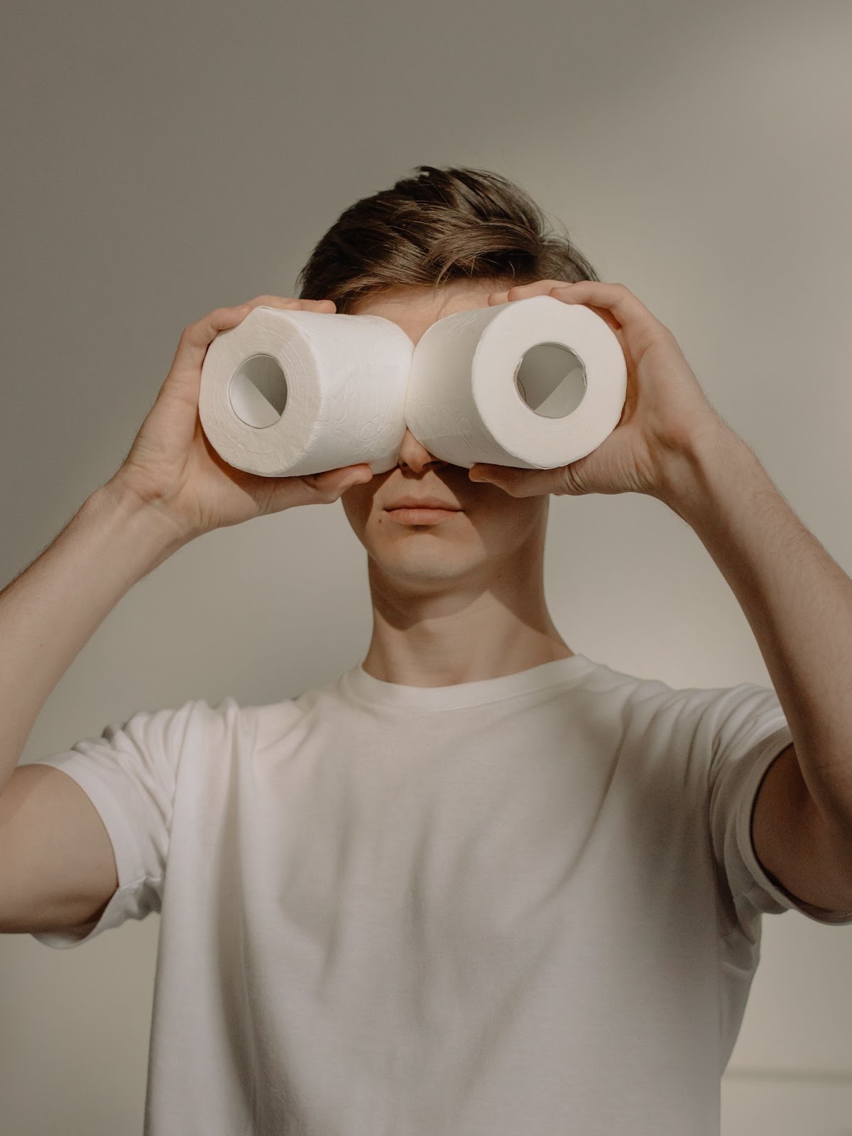 Guy holding two toilet papers against his eyes 