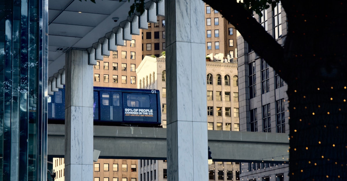 View of an elevated city tram between building columns.
