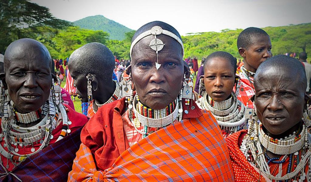 Group of fierce-looking Maasai women in traditional robes and bead necklaces