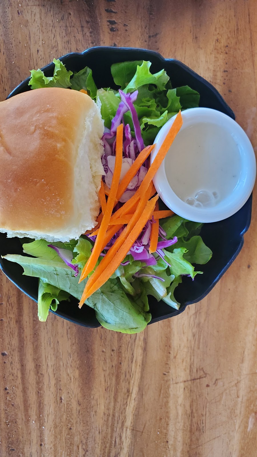 Image of a bowl of salad with a roll.