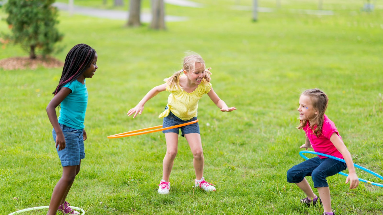 kids hula hooping in a grassy area outside