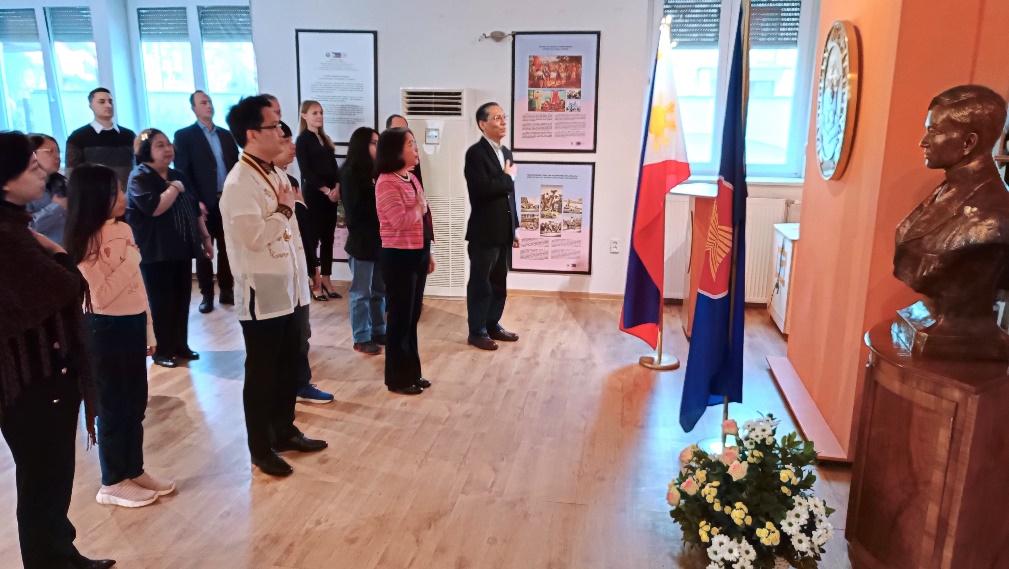 A group of people standing in a room with flags

Description automatically generated with medium confidence
