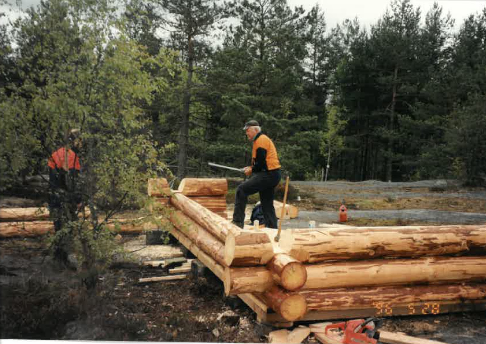 Två personer bygger ett vindskydd med stora trädstammar
