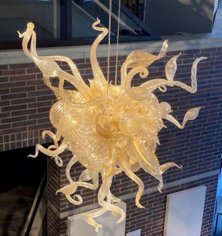 An organic yellow glass chandelier hangs from the ceiling of the musuem. 
