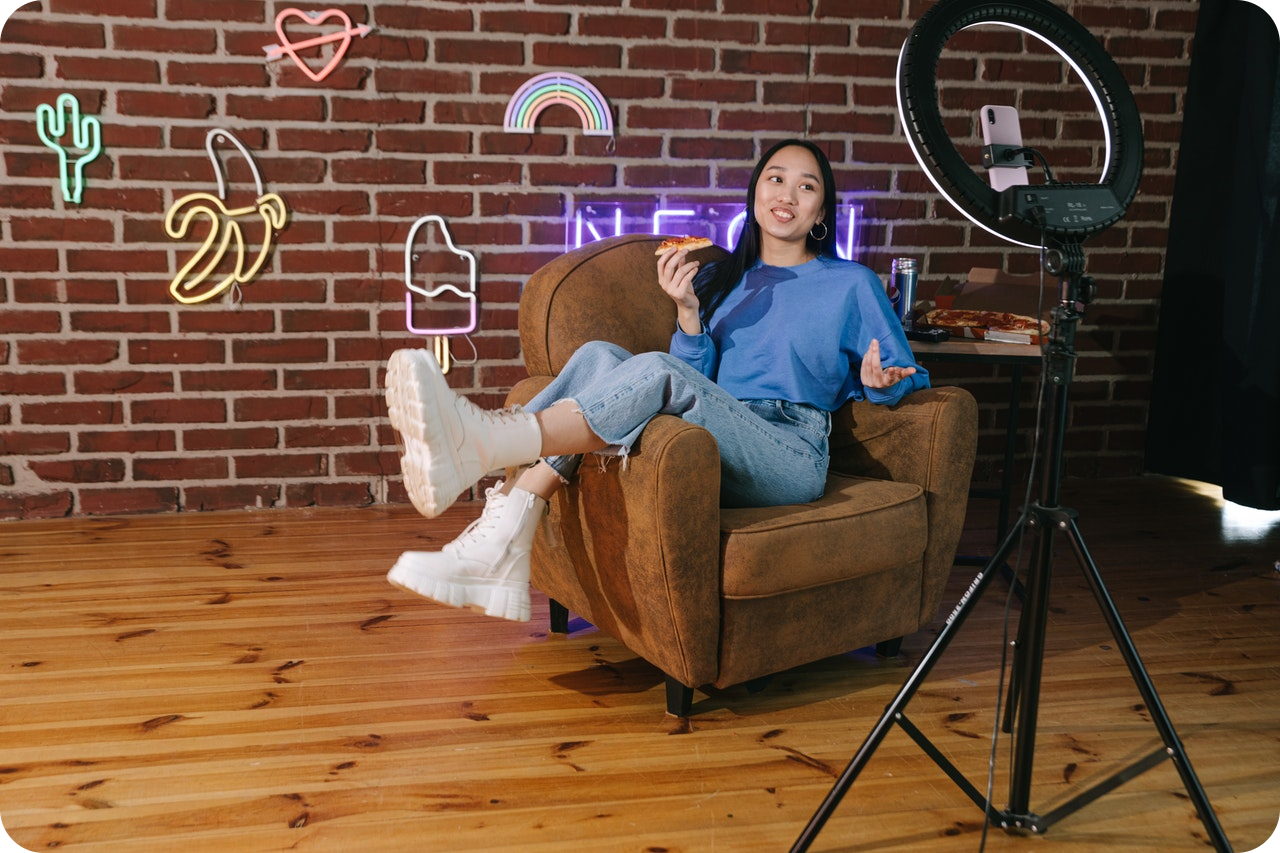 Image of reclining girl holding pizza addressing a camera