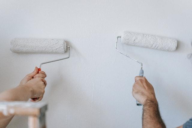 two people painting a white wall