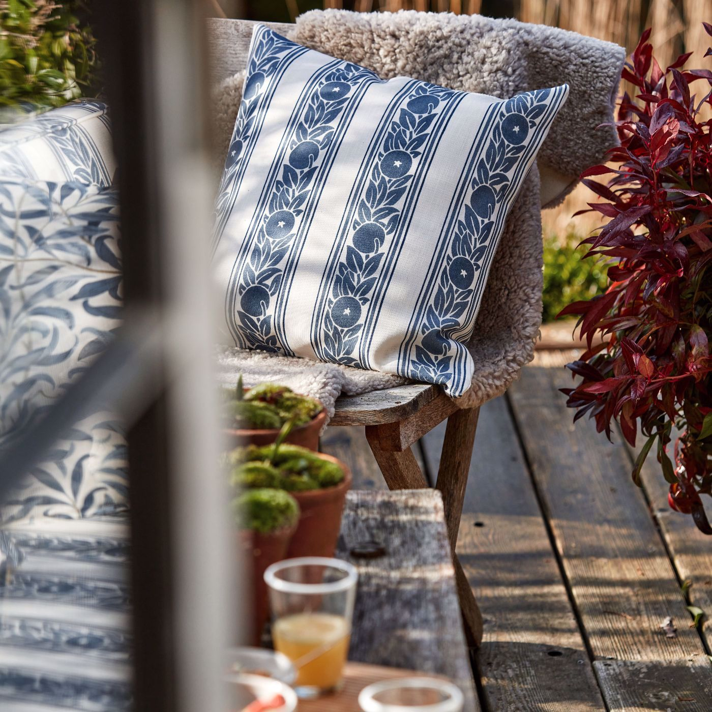 A chair sitting on a wooden deck next to a potted plant