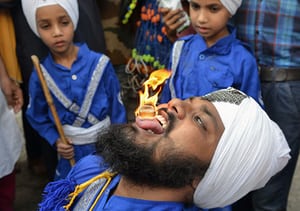 A member of the Nihang, the Sikh warrior order, holds a flaming cube on his tongue during a procession marking the 413th anniversary of the installation of the Guru Granth Sahib at the Golden Temple, Amritsar, India