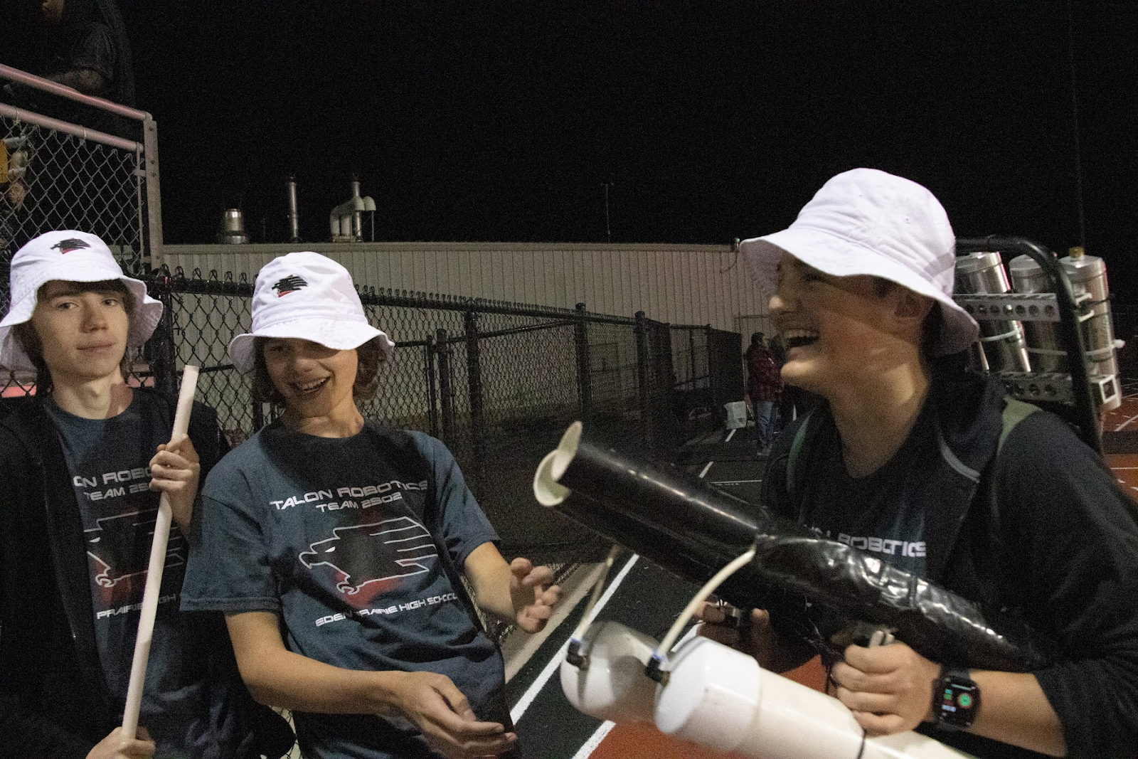 Three talon team members laughing with each other on the feild.