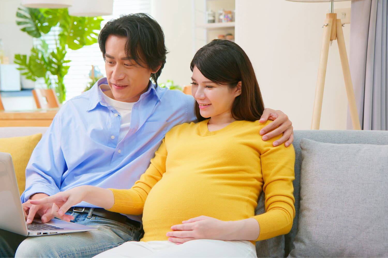 Pregnant woman and her partner looking at a laptop