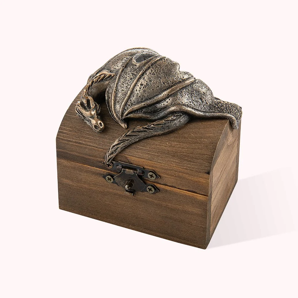 Boîte à bijoux en bois comprenant un dragon en métal couché sur le couvercle.