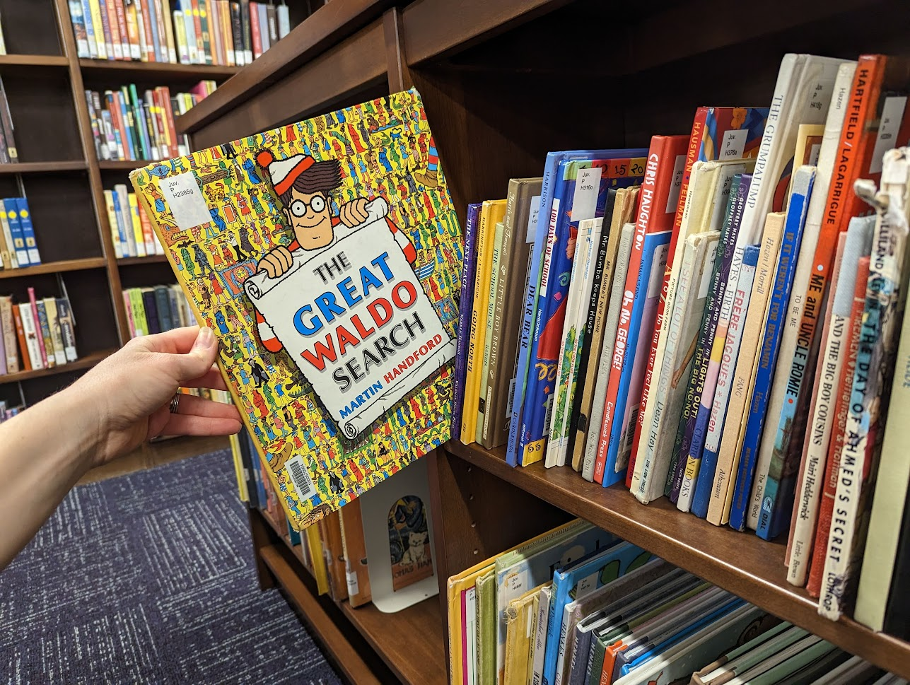 photo of Where's Waldo children's book being pulled off a shelf of other children's books