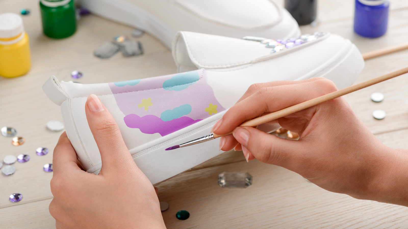 Person painting a white leather shoe.