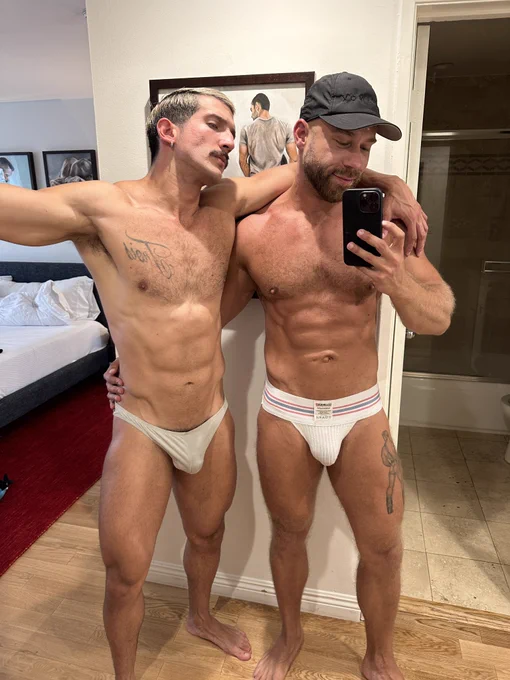 Brogan posing in white classic jockstrap with Sir Armas who is wearing seethrough white trunks
