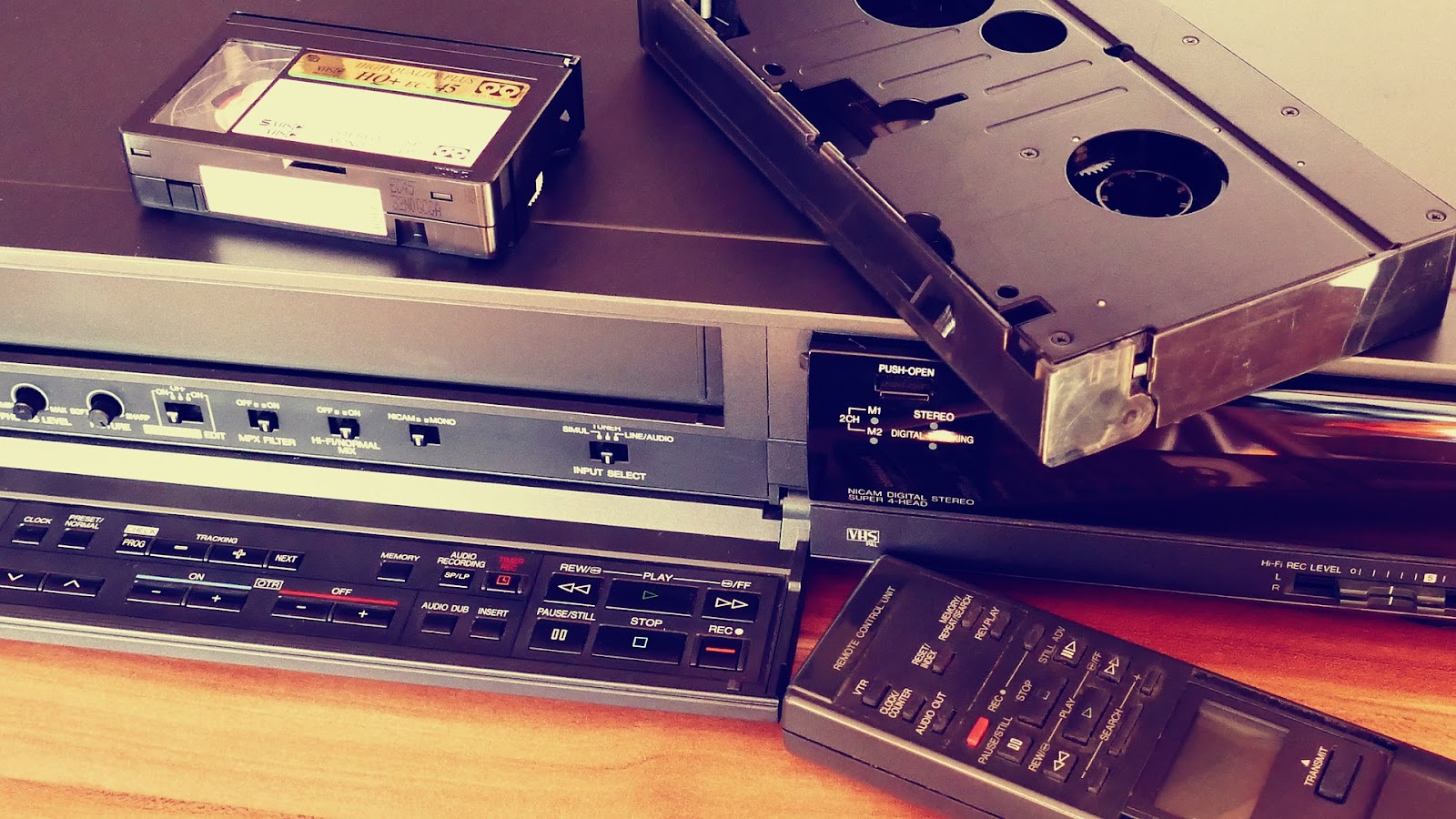 1990's technology: large and small video tapes, VCR, audio receiver, and remote