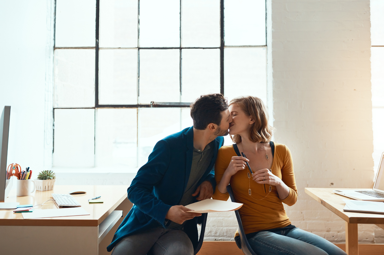 couple kissing sitting by a desk 