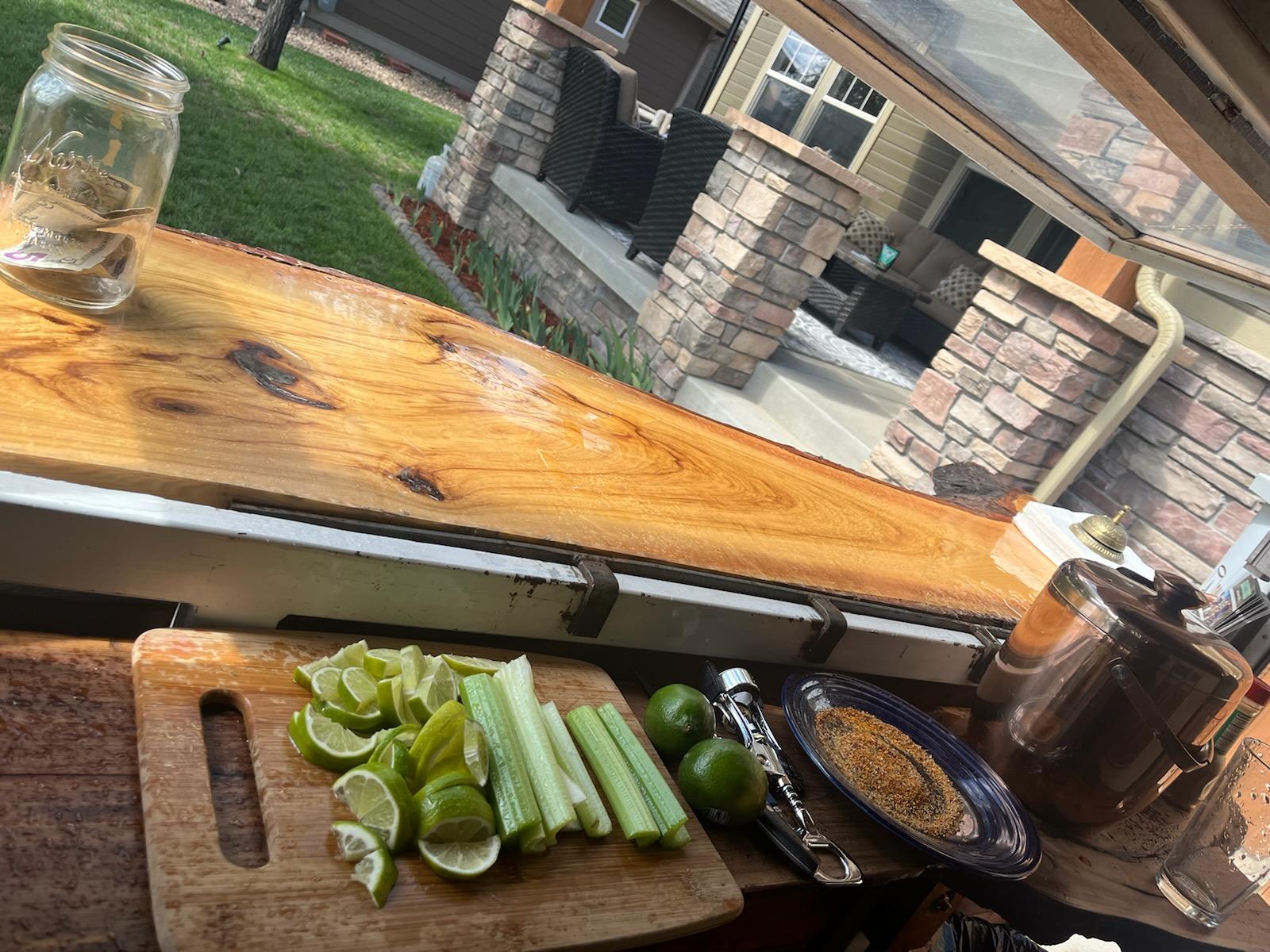 A bottle opener and lime and celery garnishes are displayed on the bar top inside the On The Rocks mobile bar trailer.