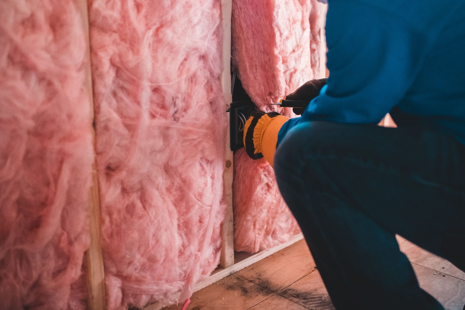 construction worker installing pink insulation