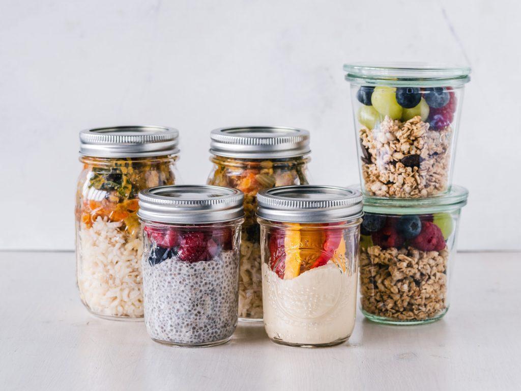 Six jars filled with different mixes of grains and fruits.