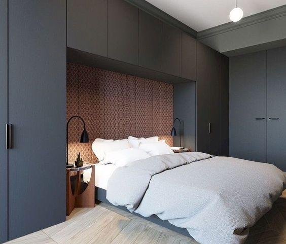 Quarto de casal com dormitório planejado cinza escuro, fundo da cama com revestimento personalizado em tom amadeirado, criado mudo de madeira, luminárias pretas e piso de madeira.
