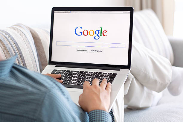 man sitting the MacBook retina with site Google on screen Simferopol, Russia - July 9, 2014: Google biggest Internet search engine. Google.com domain was registered September 15, 1997. google stock pictures, royalty-free photos & images