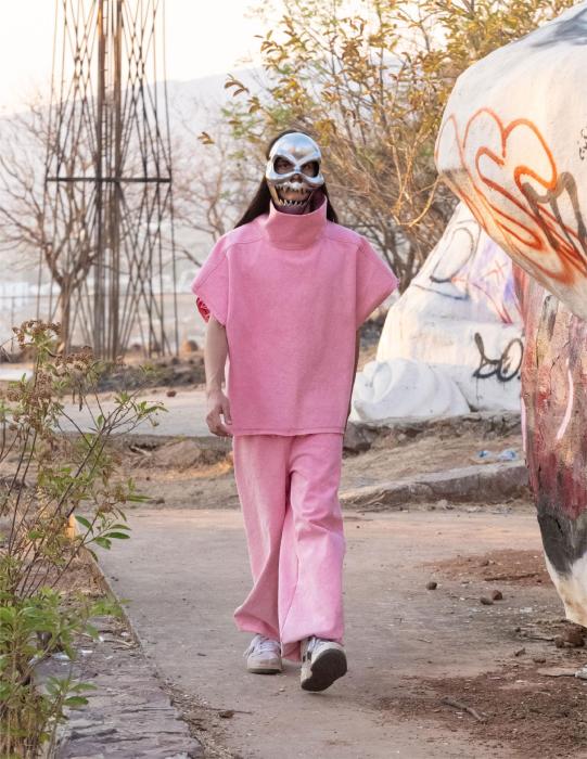 A look a model rocking a pink two-piece  with a mask on his face 