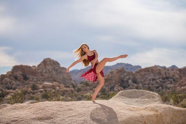 赤い衣装を身にまとい、岩肌の上に裸足でダンスする女性の写真