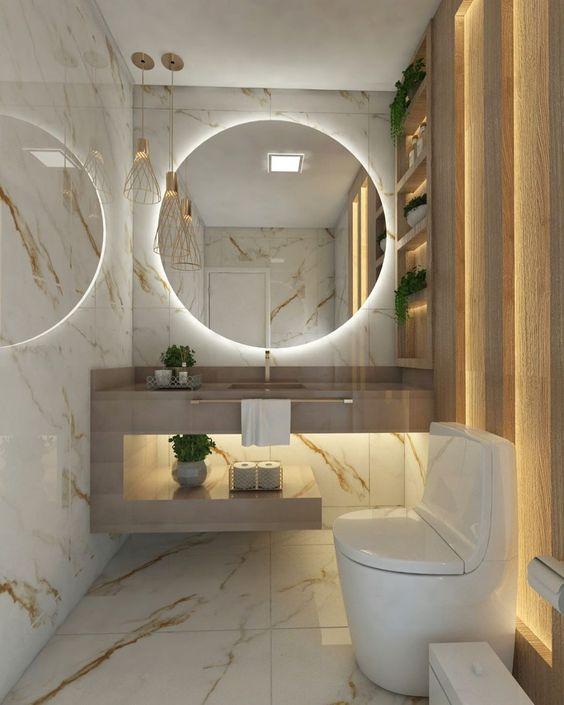 Banheiro com revestimentos na parede e piso de porcelanato marmorizado claro, bancada de porcelanato cinza, parede lateral com revestimento de madeira.